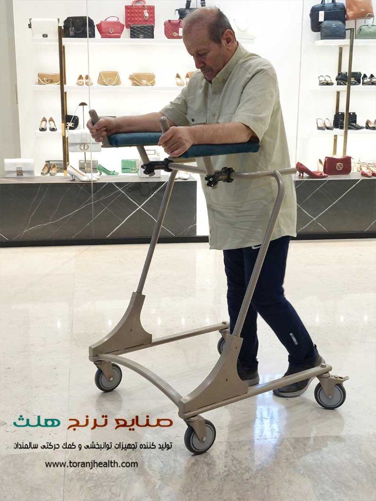 مرد سالمند برای راه رفتن از واکر چرخدار ایستاده کمک گرفته است.